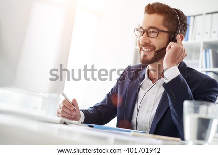 Smiling businessman using headset when talking to customer Royalty-Free Stock Photo #401701942