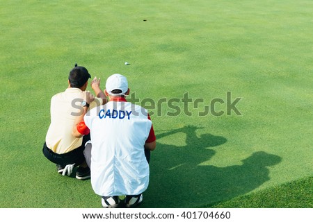 Golfer and caddy reading green Royalty-Free Stock Photo #401704660