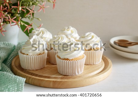 sweet vanilla cupcake with buttercream put on wooden board, image soft tone.