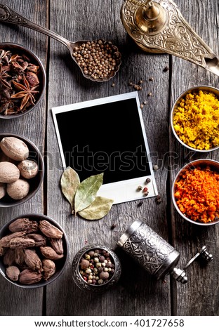 Spices, pepper grinder, blank photo frame and dry red chili peppers at wooden green background with spoons nearby
