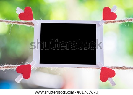 Blank instant photo and clippaper hanging on the clothesline with bokeh nature background.Designer concept.