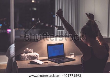 Success, victory or meeting deadline concept. Young,excited caucasian woman or teenager is holding her hands up in the air. Female teenager working late at night in her room. Success concept. Royalty-Free Stock Photo #401771593