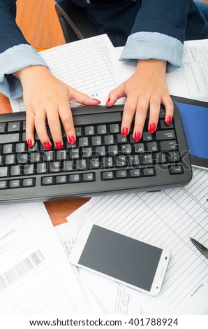 Closeup office womans fingers with red nailpolish writing on computer keyboard using both hands