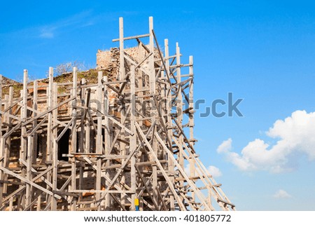 Ancient building is under construction. Wooden scaffolding and blue sky