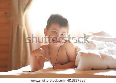 Boy watching telephone in white bed