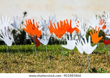 Many waving abstract hands signs or flags installed on a grassy lawn using the metal wire