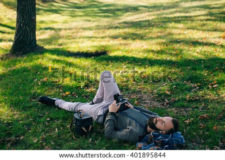 man hipster photographer  with old film camera medium format lying on the grass and dream and relax
