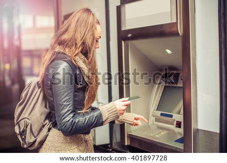 Young woman withdrawing money from credit card at ATM Royalty-Free Stock Photo #401897728