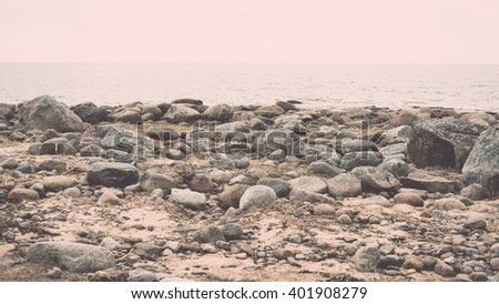 Rocky autumn beach with waves crashing on the rocks in misty weather - vintage film effect