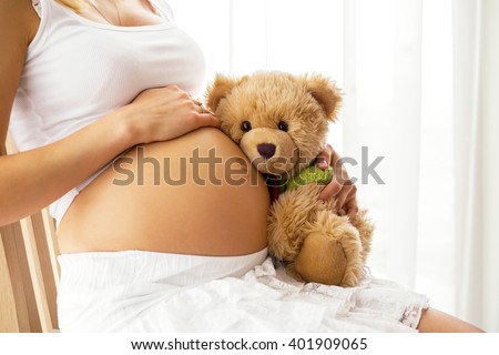 Pregnant woman holding teddy bear 