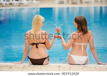 girl with cocktail in the swimming pool with blue water