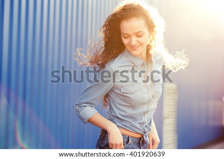 Happy danicng young woman outdoor with curly hair