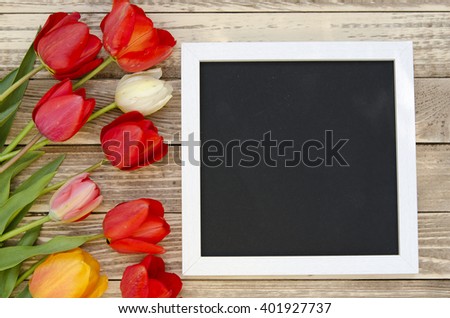 Tulips with blank black chalkboard picture frame on a wooden background. romantic picture.  