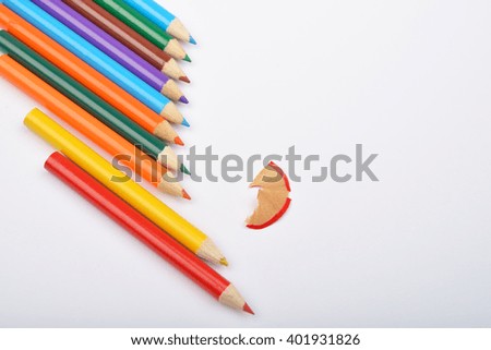 Close up of arranged colored pencils with pencil shavings on white background. Selective focus