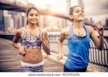 Two sportive pretty women running outdoors at sunset - Female friends training in the morning