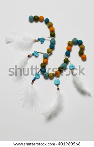 Closeup of handmade beaded bracelet with feathers on white background
