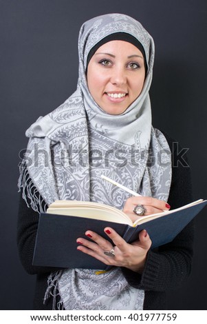 Beautiful muslim woman writing in a notebook
