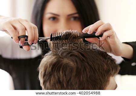 Professional hairdresser making stylish haircut Royalty-Free Stock Photo #402054988