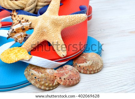 Flip-flops, starfish and seashells on a wooden background.