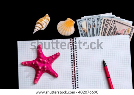 Blank open notepad with seashells, pen and dollar isolated  on black background