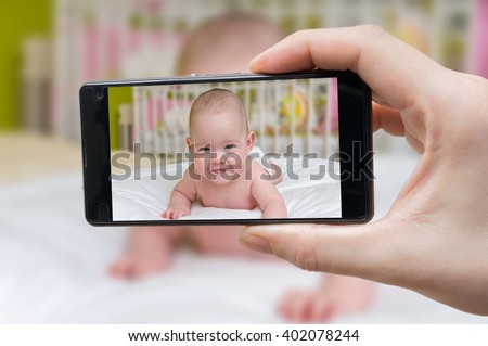 Parent is taking photo of a baby with smartphone.