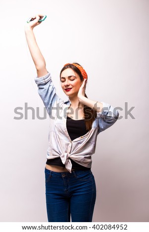 Portrait of a happy woman listening music in headphones and dancing isolated on a white background