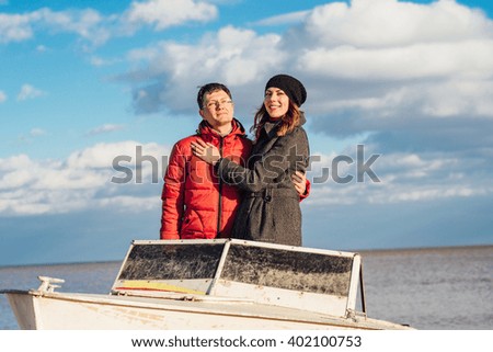 loving couple standing in an old metal boat on a sunny day on the beach