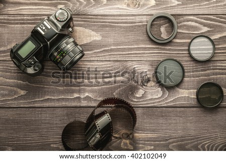 Old film photo camera with camera accessories on wooden rustic background, flat lay Royalty-Free Stock Photo #402102049