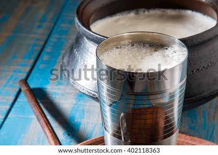 Indian sweet Lassi made up of milk, curd, sugar and salt mixed with ice cubes, served in a jumbo steel glass, prepared in traditional earthen pot 