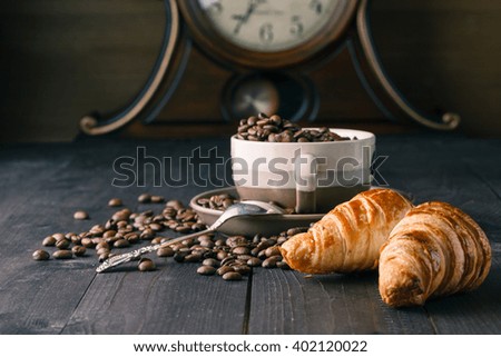 Fresh coffee beans on wood with croissant