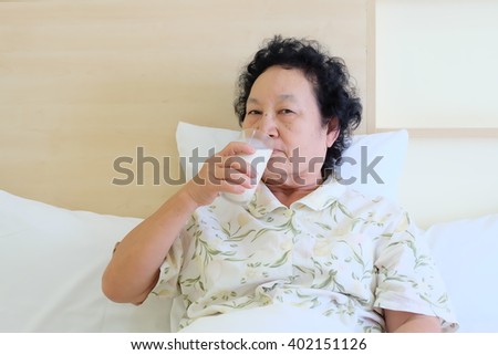 Portrait of Asian senior woman drinking milk on bed