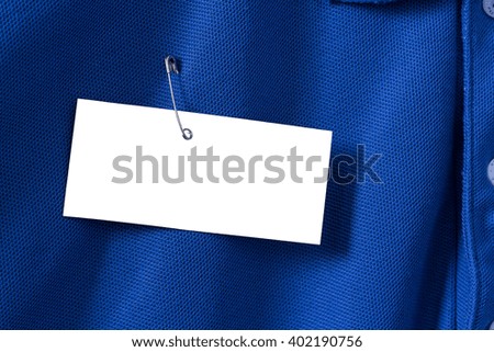 White paper tag, label on blue shirt with brooch