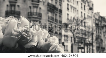 Roses and typical Parisian street at background. Aged photo. Black and white.