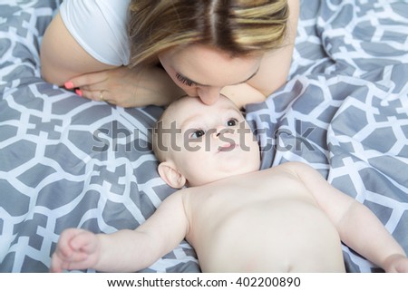 A Portrait of happy young mother with a baby in the bed at home