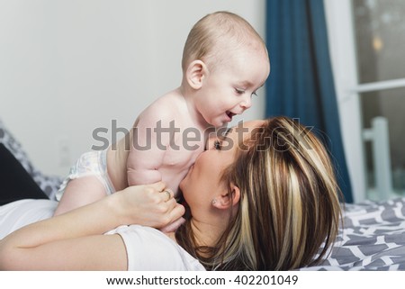 A Portrait of happy young mother with a baby in the bed at home