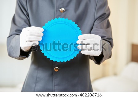 Concierge in hotel holding a blank blue badge in his hands