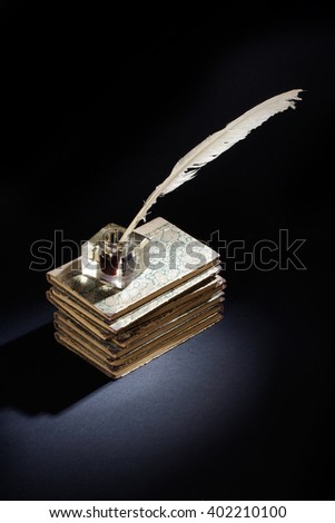 Old fountain pen, books and inkwell on a black background