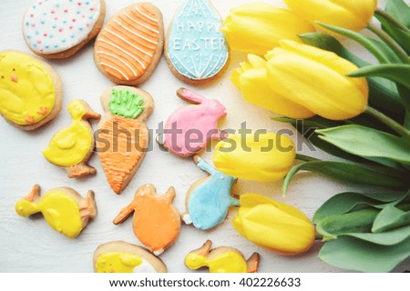 Easter cookies and yellow tulips on a wooden background