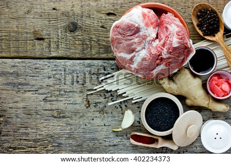 Ingredients of Japanese and Chinese cuisine: udon noodles, meat, sesame, ginger, spices, seasoning, soy sauce, garlic on a wooden background blank space for text top view