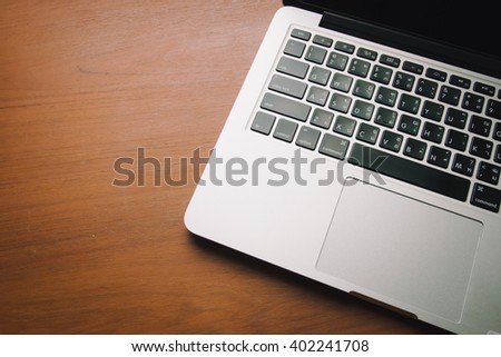  Laptop with isolated screen on old wooden background.Vintage style photo with custom white balance, color filters, soft focus effect, and some fine film grain added