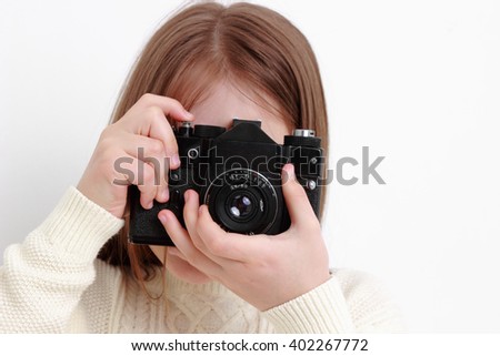 Smiling young girl holding photo camera and taking pictures