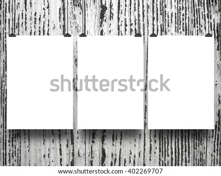 Close-up of three blank frames hanged by clips against grey scratched wooden background 