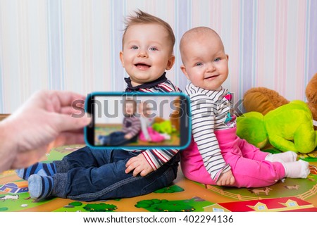 Making photo of boy and girl twins by the smartphone camera