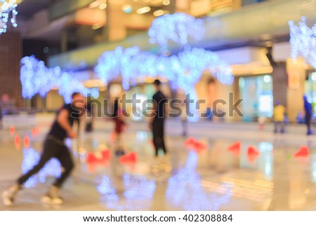 Blurred people skating on the ice rink that decoration with light bulbs.