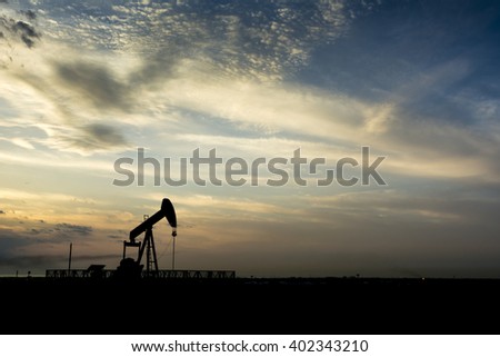 Cloudy sunset and silhouette of crude oil pumping unit in the oil field - Bahrain

