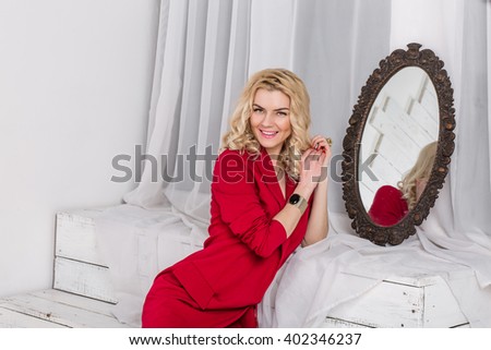 Serious young woman sitting in the studio look a serious sadness. a psychological portrait, looking in the mirror white background red jacket