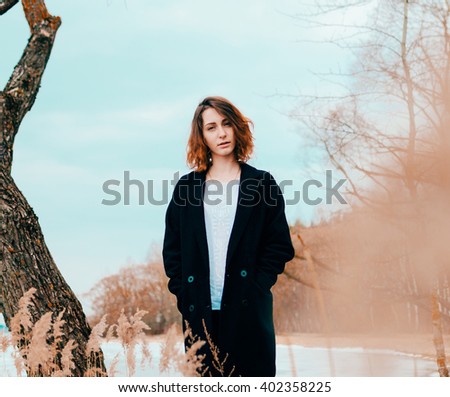 Young pretty girl on the beach of lake in spring time