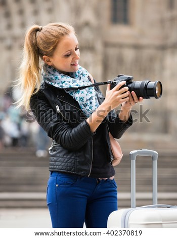 Happy girl taking pictures of sights at city excursion