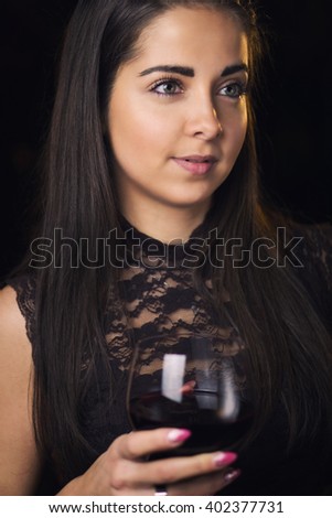 Beautiful brunette sommelier holds a glass of wine in her hand. Color effects and custom white balance are used on this picture.