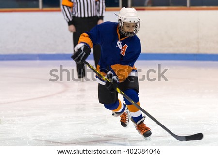 Young minor ice hockey player skating during a game in an arena